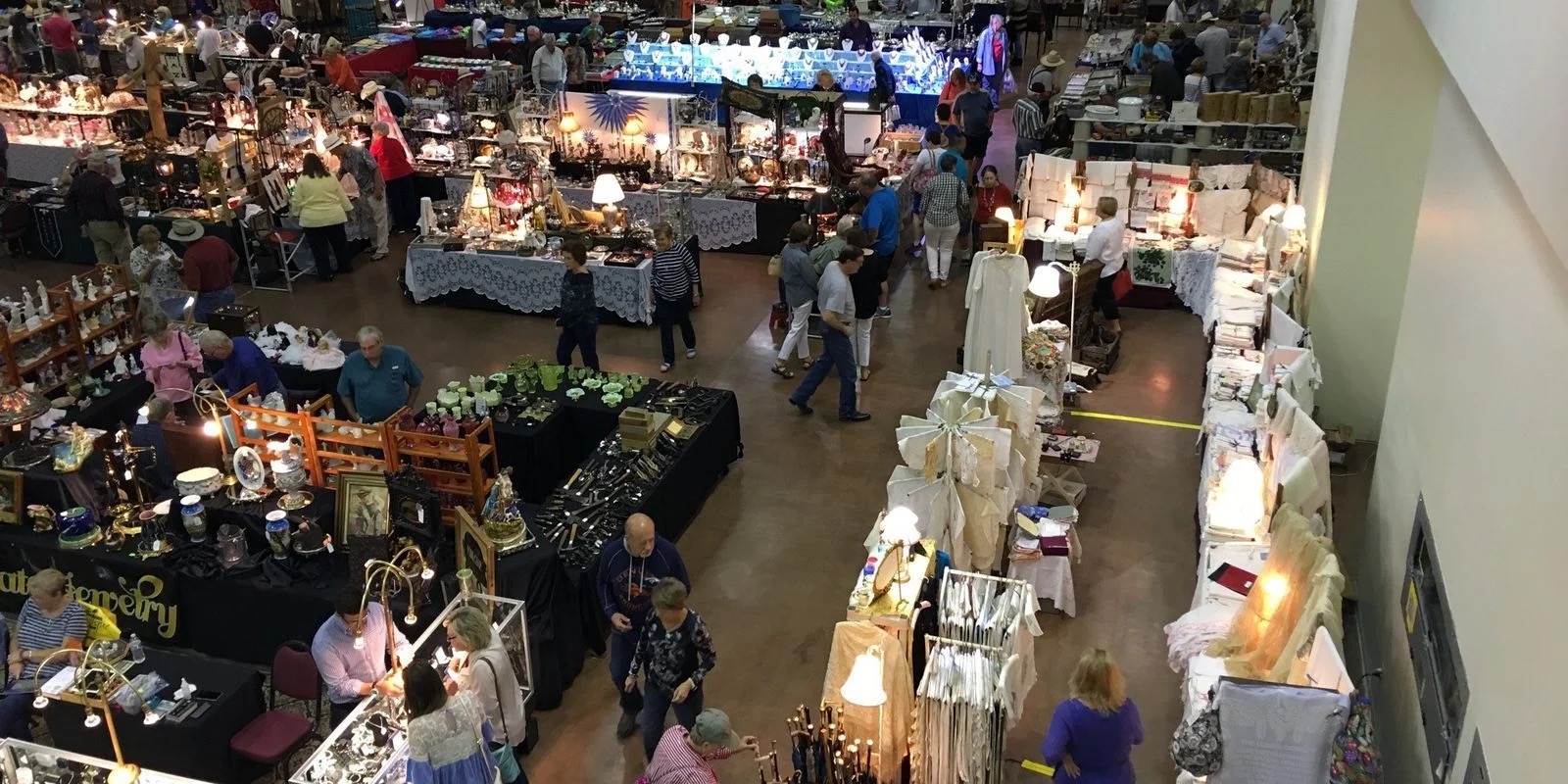 The Exhibit Hall floor during a real antiques and vendor show, rows of dealer booths and browsing attendees.
