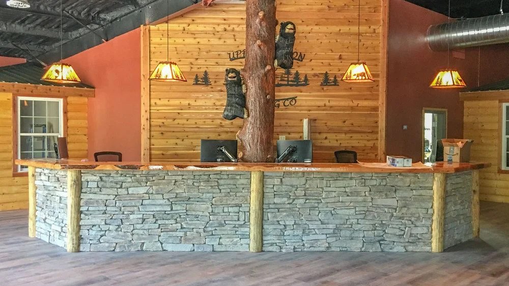 The front desk at Upper Canyon Lodging Company, log-and-stone construction with a carved bear motif on the wall.