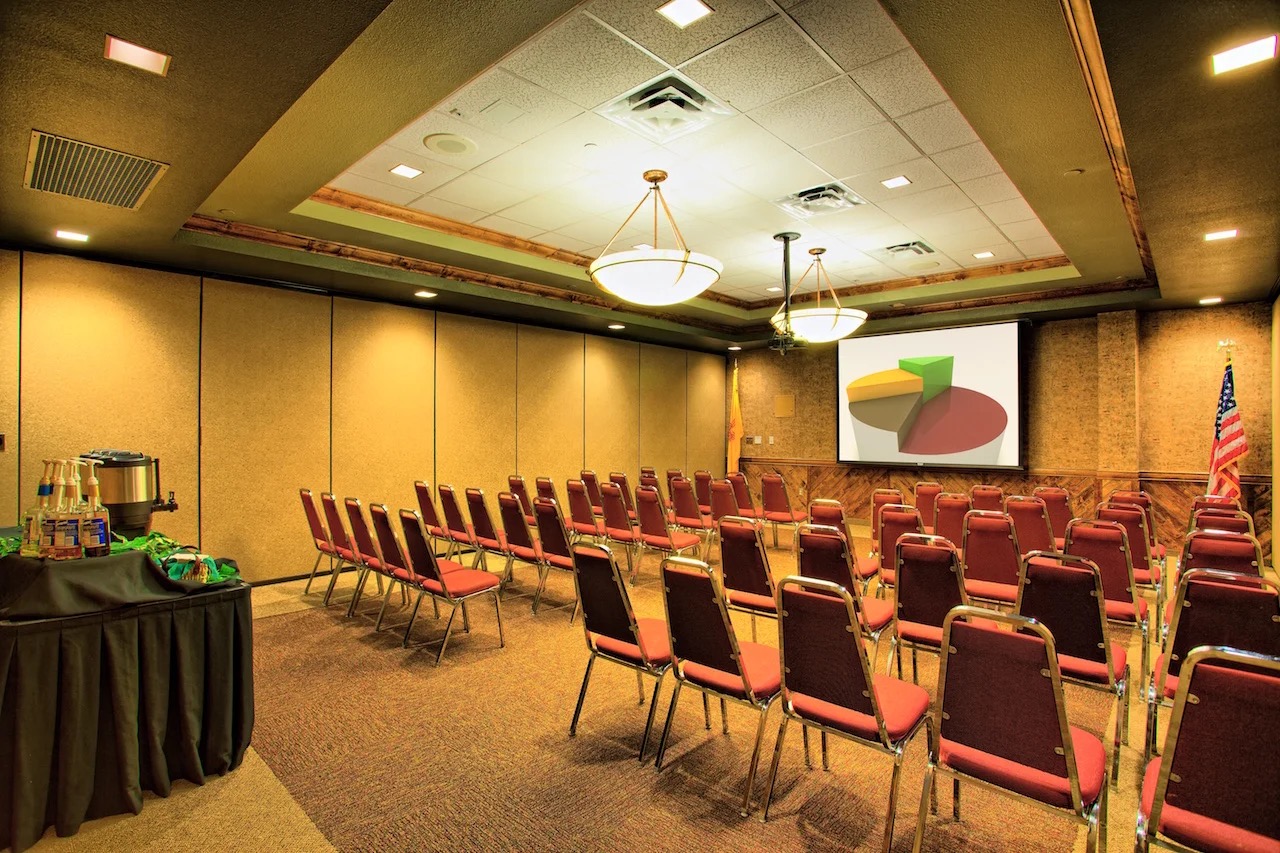 A Ruidoso Convention Center meeting room set theater-style with rows of maroon stacking chairs facing a projection screen. This is a representative photo of an RCC breakout room, not a photo of this specific room — the Village does not publish a photo per room.